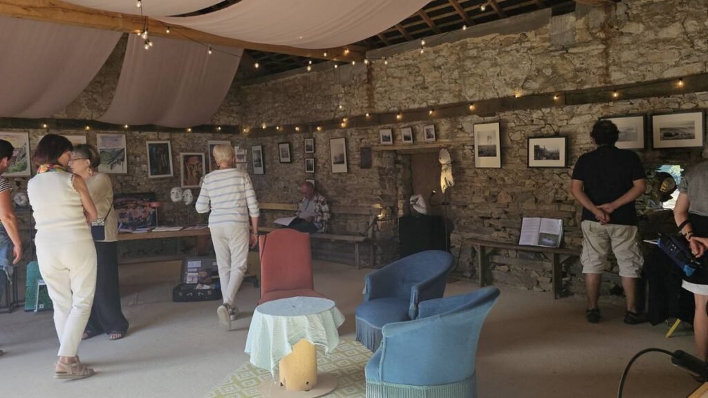 Visiteurs découvrant l’exposition dans la grange en pierre